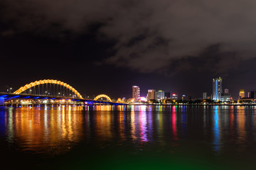 Obraz premium Night scene of Han river, illuminated Dragon bridge and buildings in DaNang city, Vietnam