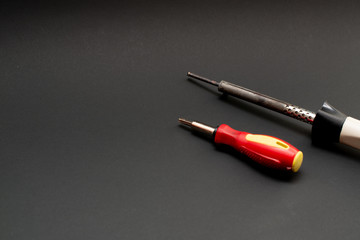 electric soldering iron and screwdriver on a black background