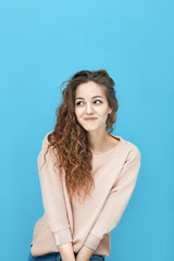 Obraz premium Portrait of a young beautiful woman wearing sweatshirt holds hands in front in a shy pose isolated over blue background