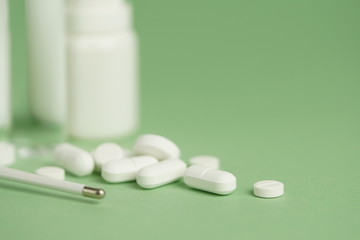 White medical pills and medical preparations in with bottles, glass ampoues,close-up on green background. Closeup photo of medical preparations with copy spaes.