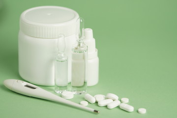 White medical pills and medical preparations in with bottles, glass ampoues,close-up on green background. Closeup photo of medical preparations with copy spaes.