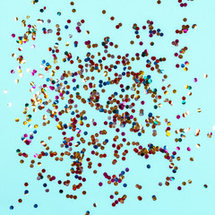 Gold colorful confetti on blue background. Festive backdrop of sparkles for birthday, carnival