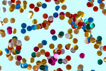 Gold colorful confetti of large size on blue background. Festive backdrop of sparkles for birthday, carnival