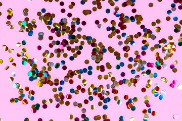 Gold colorful confetti of large size on pink background. Festive backdrop of sparkles for birthday, carnival