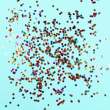 Gold colorful confetti on blue background. Festive backdrop of sparkles for birthday, carnival