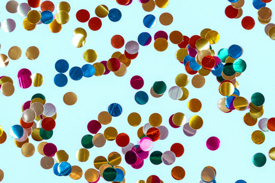 Gold colorful confetti of large size on blue background. Festive backdrop of sparkles for birthday, carnival