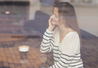 Attractive young woman sitting in city cafe.