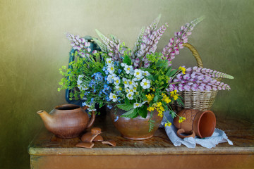 Still life with a bouquet of wild flowers in a clay vase on the table