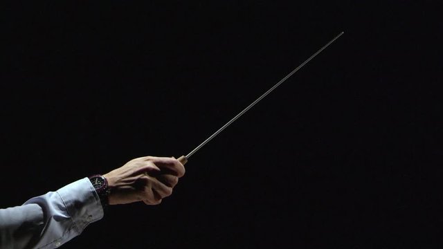 Male hand with a conductor&rsquo;s stick on a black background. Macro shooting in studio