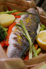 Grilled seabass with vegetables and lemon.Served on paper.Close up