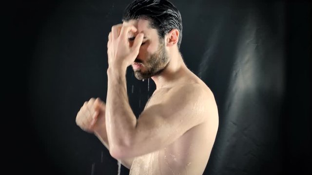 Young Bare Muscular Young Man Receiving Water Splashes in Studio