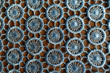 Background - light blue crochet lacy fabric on wood from above