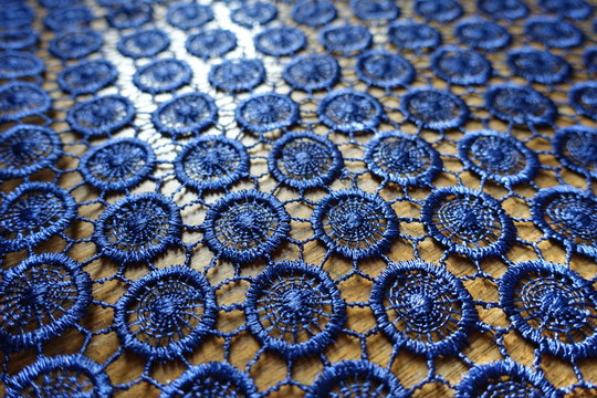 Close shot of dark blue crochet lacy fabric on wood