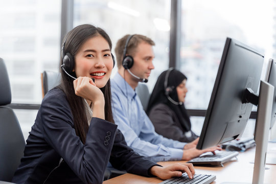 Happy smiling asian woman call center and operator wearing headsets working on computer and talking with customer with her service mind