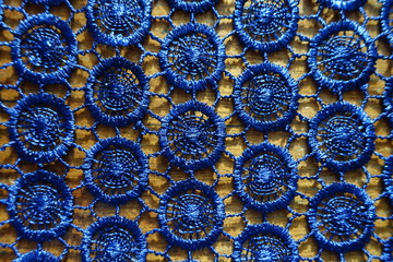 Shiny dark blue crochet lacy fabric on wood from above