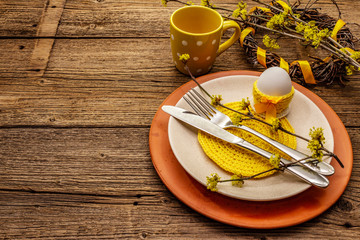 Easter table setting on old wooden background. Spring holiday card template. Cutlery, crochet napkin, egg, flowering sprigs of dogwood