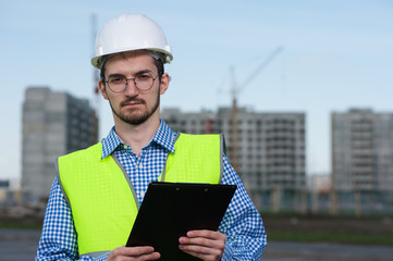 Portrait of Young Man Engineer In Green Vest With Plan