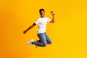 Young african man jumping as crazy, carefree, celebrating victory