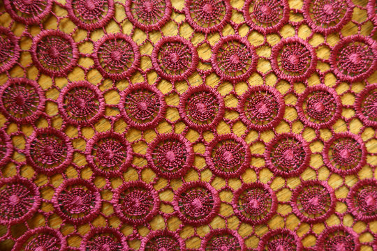 Texture of red crochet lacy fabric on wood from above