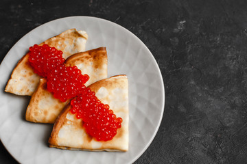 Maslenitsa Maslenitsa week is a holiday of food. Pancakes with red caviar on a plate with Cutlery. The view from the top. side view. space for text