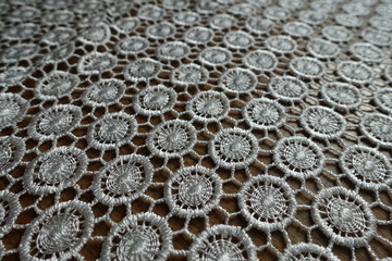 Close view of ivory white crochet lacy fabric on wood