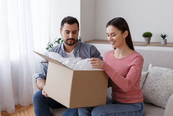 Happy young husband and wife customers open box purchase