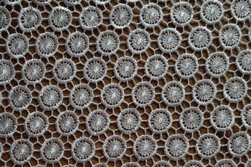 Surface of ivory white crochet lacy fabric on wood from above
