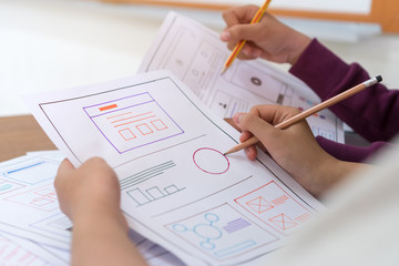 asian startup designer creating user experience UX web on smartphone or mobile layout development. UI application on paper prototype framework production before on web for device in technology develop