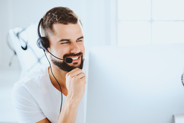 Young smiling customer support operator with hands-free headset working in the office. Concept