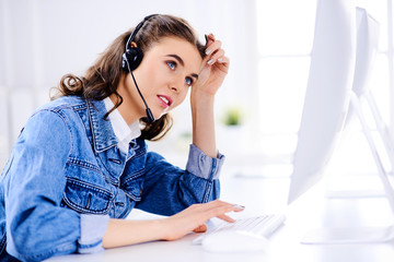 Naklejka premium Tired female customer support operator in the office with headset