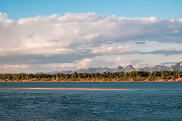 A small sand dune in the middle of the Mekong River with a view of Laos mountain scenery
