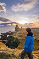 young asia man standing to see sunset in afternoon at volcanic rock  coast at Londrangar famous cliffs in west iceland vertical