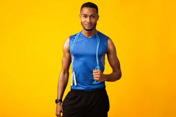 Handsome black sportsman with jumping rope at studio