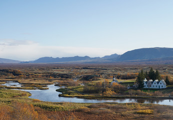 Old church and small village with stream and mountain background near Thingvellir national park, Iceland