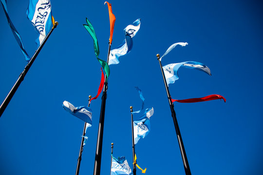 View from below of flags of all colors, red, green, white and blue fluttering in the wind with blue summer sky in the background, close-up and horizontal image