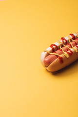 one yummy hot dog with sausage, mustard and ketchup on yellow
