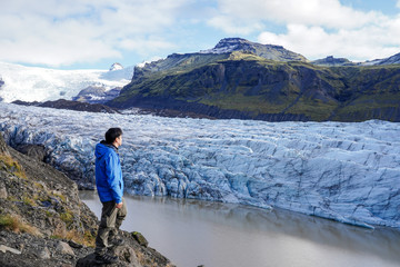 Young Asia man trekking to view point of glacier and standing to look around at svinafellsjokull,...