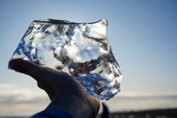 ice piece on hand in afternoon time sun shining the clear ice make reflect light