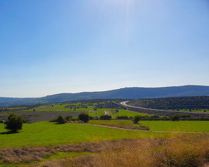 Obraz premium Green Brown Field, Road, Mountains and Blue Sky