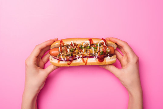 Cropped View Of Woman Holding Tasty Hot Dog In Hands On Pink