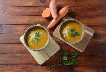Sweet potato and carrot soup served with sour cream in wooden bowl. Orange vegetable soup concept. Vegan food