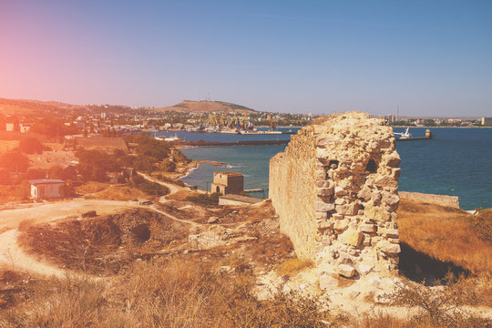 Ruins of the Genoese fortress of Caffa (Feodosia) Crimea. Rocky seashore. Sea nature landscape. View of the sea and Feodosia city from the mount. Port, harbor.