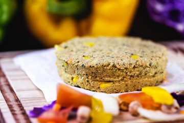 homemade vegan hamburger without meat, made from vegetables on rustic wooden background with colorful vegetables. Vegetarian life and vegetarian life concept.