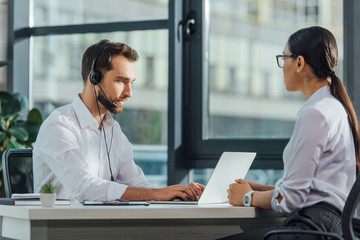 professional male translator working online with laptop and headset on meeting with businesswoman