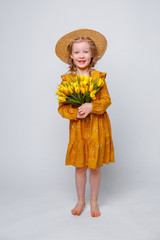 little  girl in a straw hat holding  bouquet of spring flowers, isolated on a white background. Child girl with a bouquet of yellow tulips