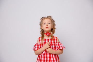 Funny smiling baby girl summer dress  on white background . Baby girl with a lip accessory on a stick.