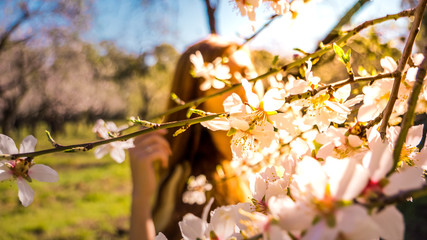Head shot of a young healthy woman enjoying outdoors with early spring flowers that bloom first