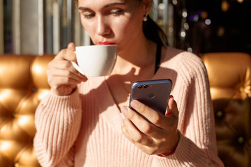 Charming woman with phone in cafe. Bright sunny morning in cafe