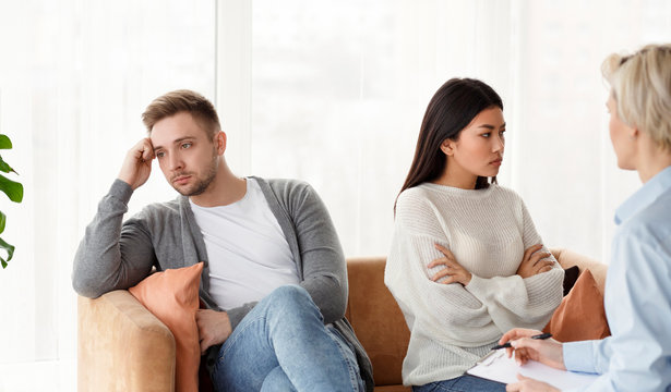 Multiracial Couple After Quarrel Not Talking Sitting In Psychologist's Office