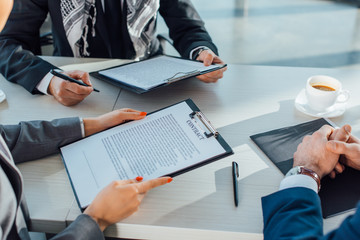 cropped view of business partners holding contract on meeting in office